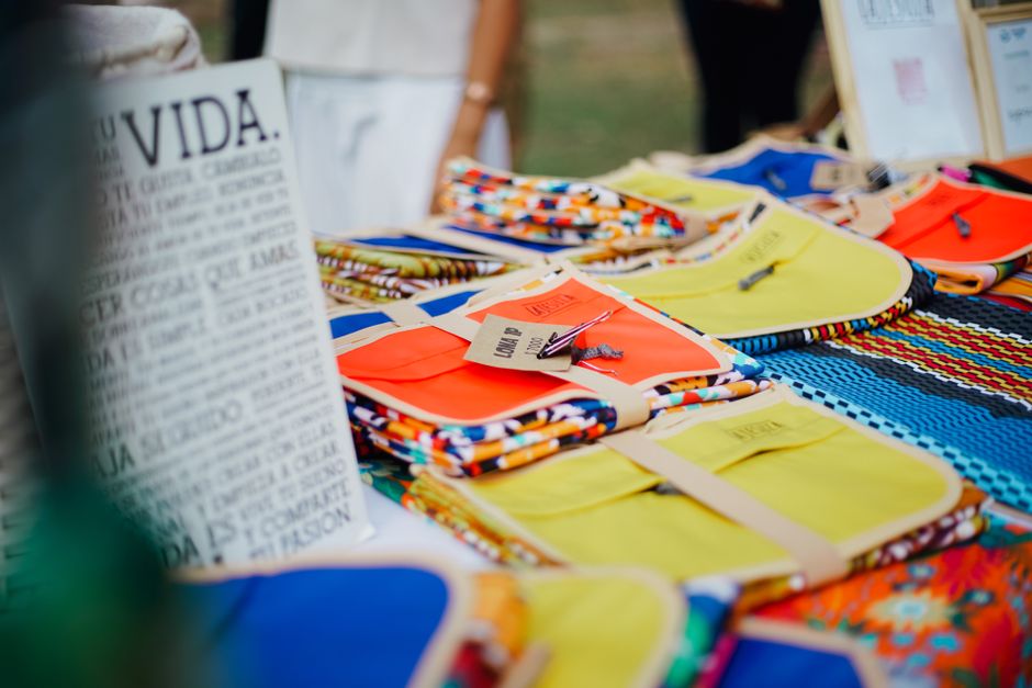 A vibrant artisan market stall displaying a variety of colorful, hand-woven textiles and crafts, highlighting global and local sourcing of meaningful decor.