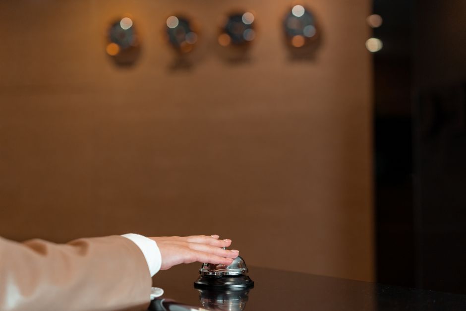 A hotel employee at a check-in desk warmly greeting a guest, holding a welcome packet, emphasizing personalized service.