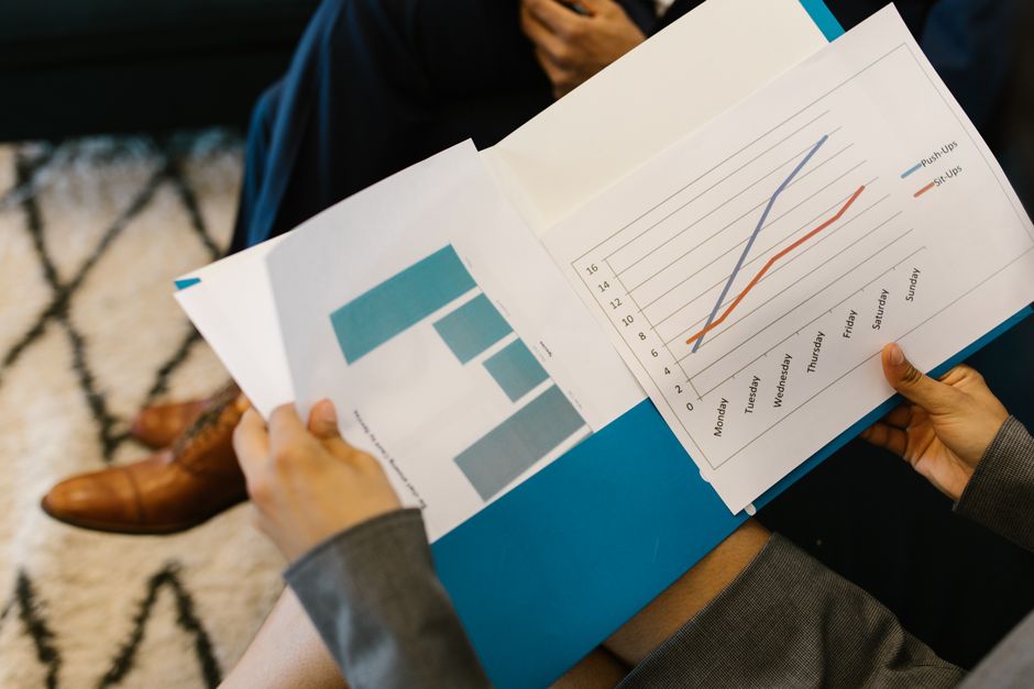 A small business owner sits at a desk, intently reviewing information on a tablet, with traditional notebooks and pens nearby, symbolizing a balanced approach to AI and human verification.