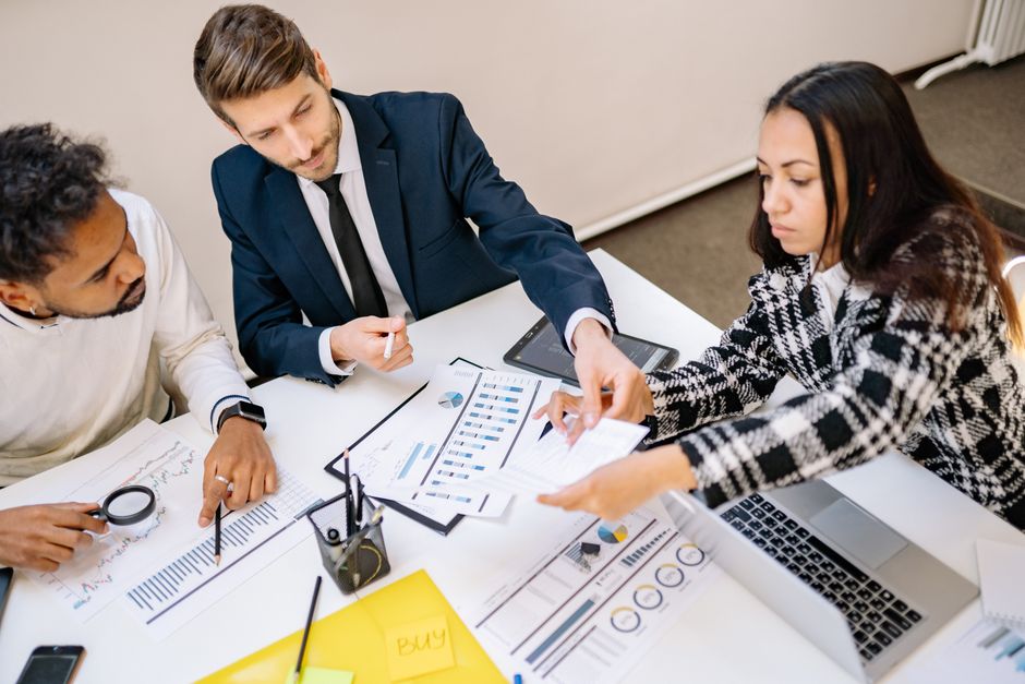 A diverse team of professionals in a modern office, analyzing data on screens and discussing strategies.
