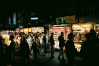 A vibrant, bustling street food market in Southeast Asia, with various food stalls and people mingling, capturing the energy of spontaneous dining.