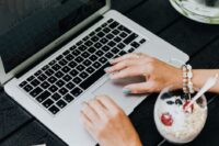A busy professional in a modern office setting enjoying a bowl of yogurt with berries at their desk, illustrating healthy eating during a packed schedule.