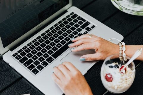 A busy professional in a modern office setting enjoying a bowl of yogurt with berries at their desk, illustrating healthy eating during a packed schedule.