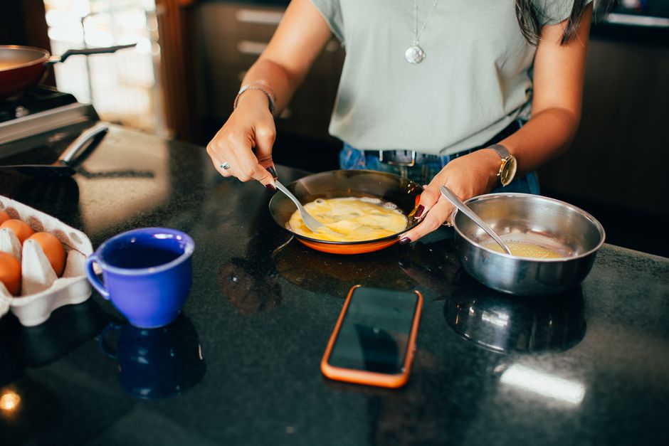 A person quickly assembling overnight oats in jars in a modern kitchen, with other prepped breakfast items visible, emphasizing efficiency.