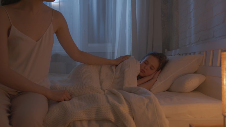 A neatly made bed with soft lighting, a book on the nightstand, and no electronic devices, depicting an ideal sleep environment.