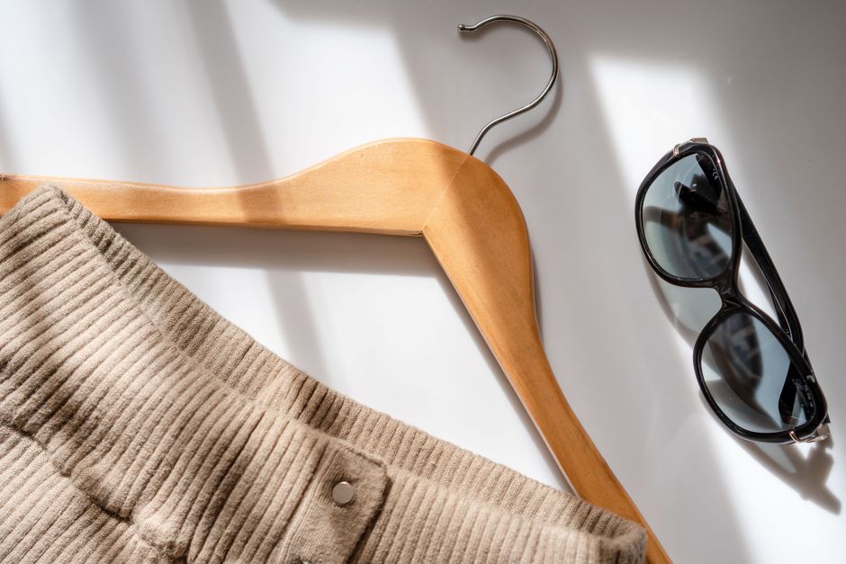A well-organized flat lay of French wardrobe staples including a white shirt, black blazer, classic denim, and ballet flats, all in neutral tones.
