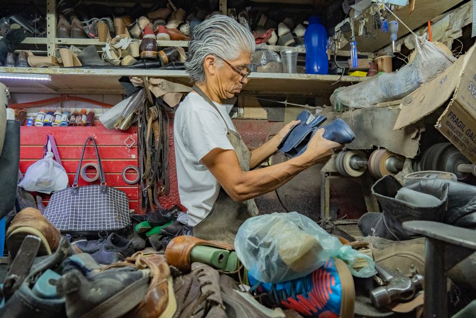 Close-up of a skilled cobbler's hands meticulously stitching the sole of a classic leather dress shoe in a traditional workshop.