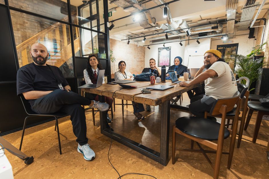 A diverse team of professionals engaged in a focused discussion around a table, illustrating strategic planning for client success and ongoing value creation.