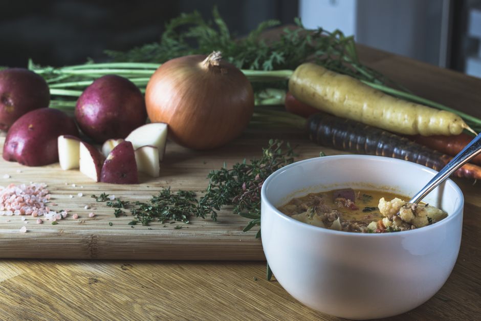 A vibrant array of chopped fresh vegetables including carrots, celery, onions, and kale, neatly arranged on a cutting board, ready for soup preparation.