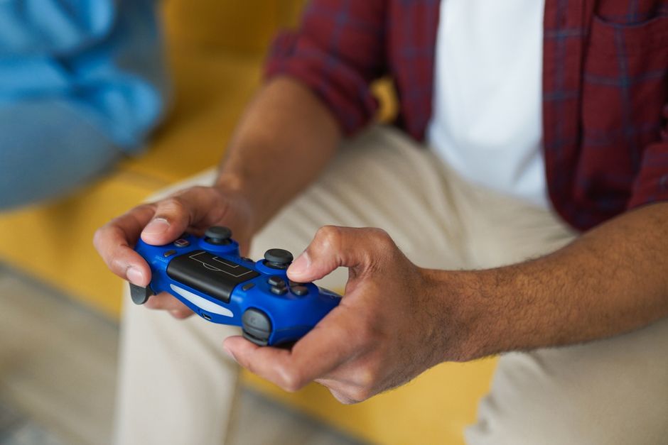 Close-up of a student wearing headphones, concentrating on a short story game on a console during a study break.
