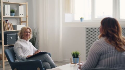 An independent consultant actively listening to a client speak, perhaps over coffee, with a notepad visible.