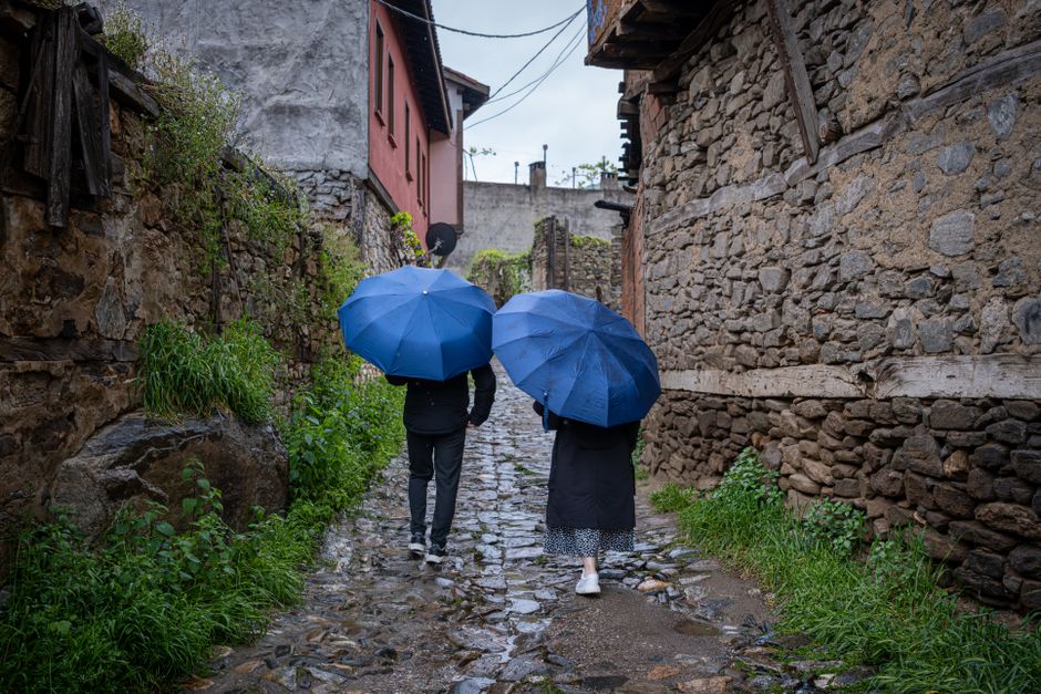 A couple under an umbrella explores the charming, cobblestone streets of a historic European city on a rainy but picturesque day.
