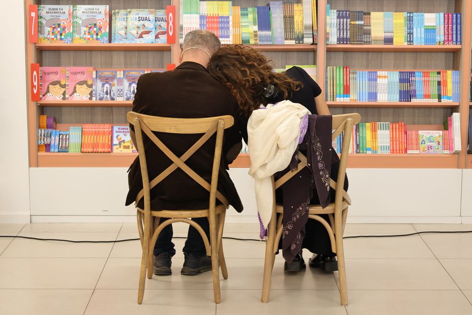 A couple absorbed in books, sitting comfortably within the grand, historic interior of El Ateneo Grand Splendid bookstore in Buenos Aires, showcasing its theater architecture.