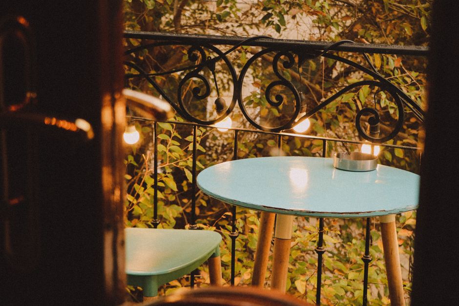A modern small balcony featuring a wall-mounted vertical garden system filled with herbs and small flowers, next to a compact outdoor stool.