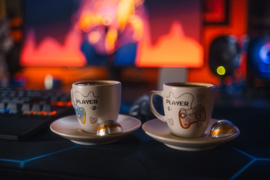 A cozy gaming nook featuring a PC monitor displaying a tranquil exploration game, with a warm blanket, a steaming mug of tea, and a gaming controller resting on a side table, emphasizing relaxation.