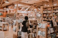 Interior of a charming independent bookstore with bookshelves stacked high and a person browsing titles, evoking a slow travel literary city break.