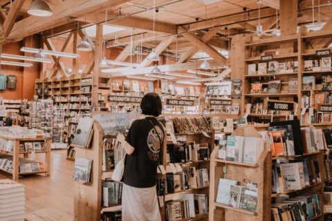Interior of a charming independent bookstore with bookshelves stacked high and a person browsing titles, evoking a slow travel literary city break.