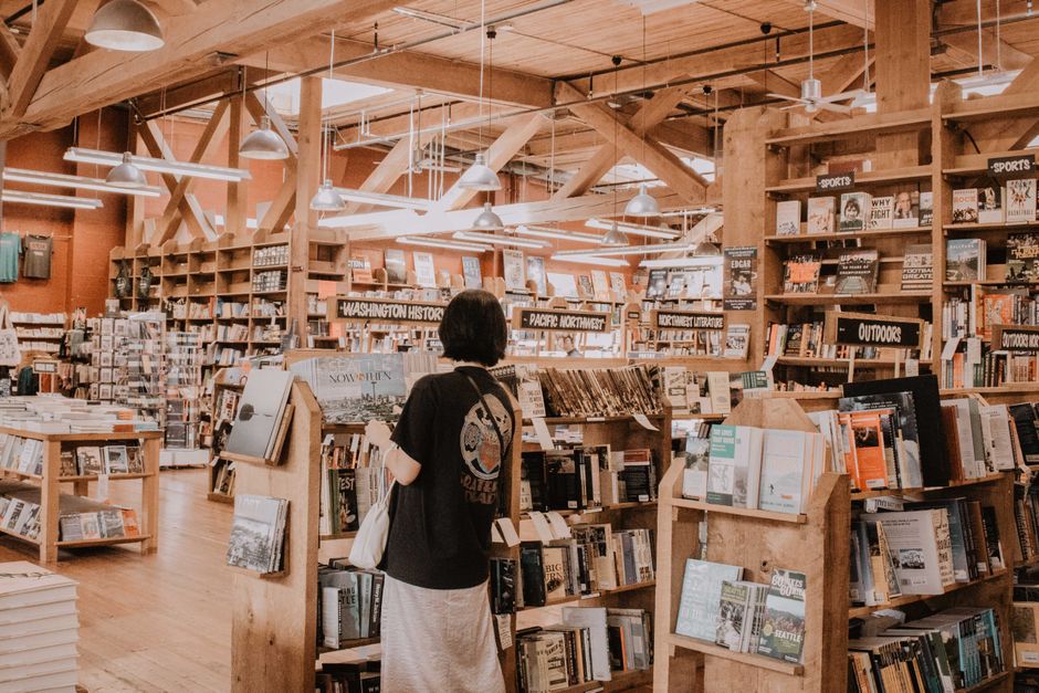 Interior of a charming independent bookstore with bookshelves stacked high and a person browsing titles, evoking a slow travel literary city break.