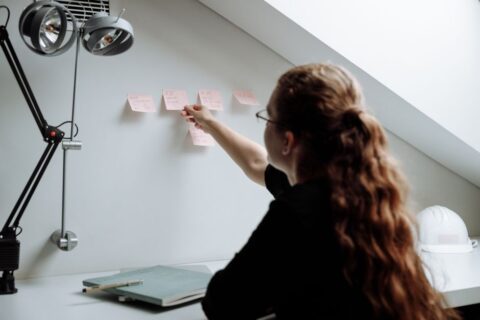 A creative professional with neat notes and a digital tablet, interacting with an AI interface that visualizes knowledge connections, symbolizing organized information.