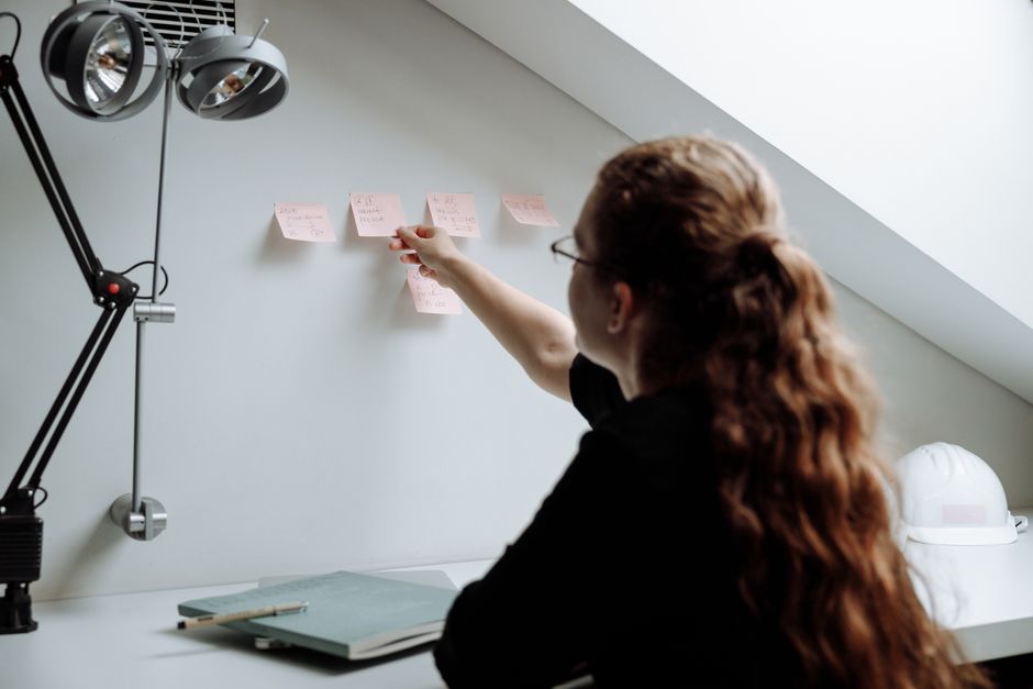 A creative professional with neat notes and a digital tablet, interacting with an AI interface that visualizes knowledge connections, symbolizing organized information.