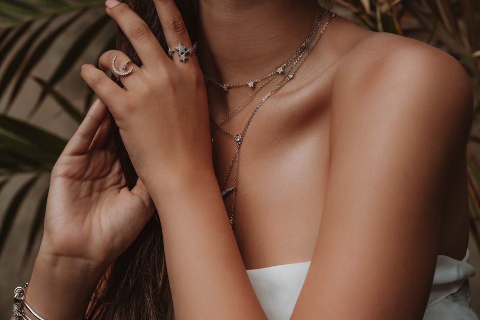 A selection of delicate gold chain necklaces layered together, some with tiny pendants, arranged on a smooth, light surface, showcasing subtle elegance for a minimal wardrobe.