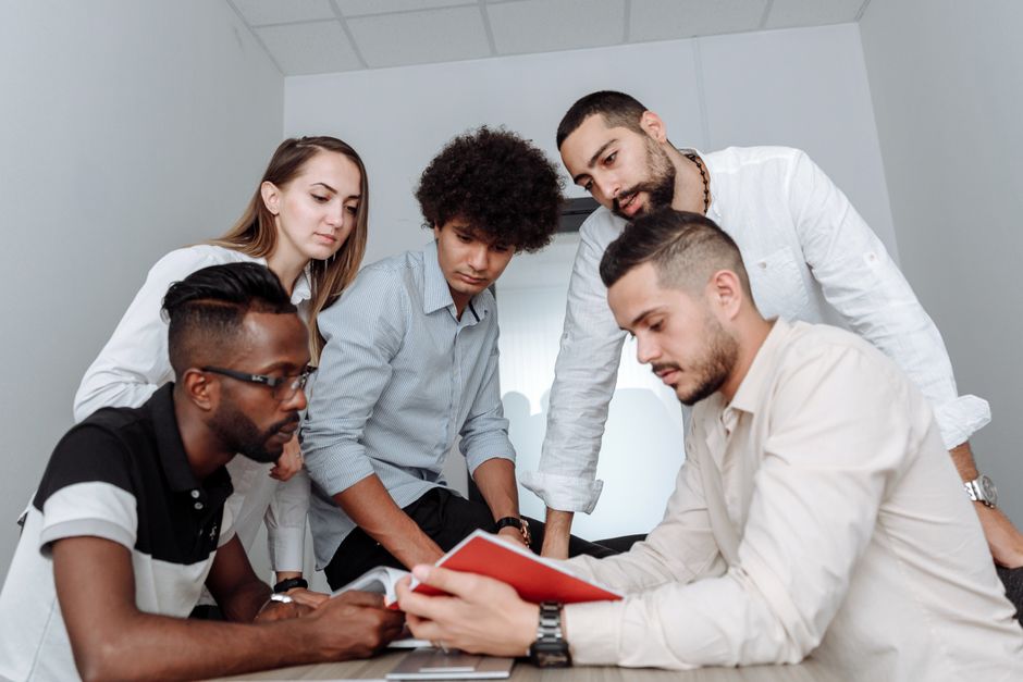 A diverse group of professionals from different backgrounds collaborating around a table, representing international teamwork and cultural exchange.