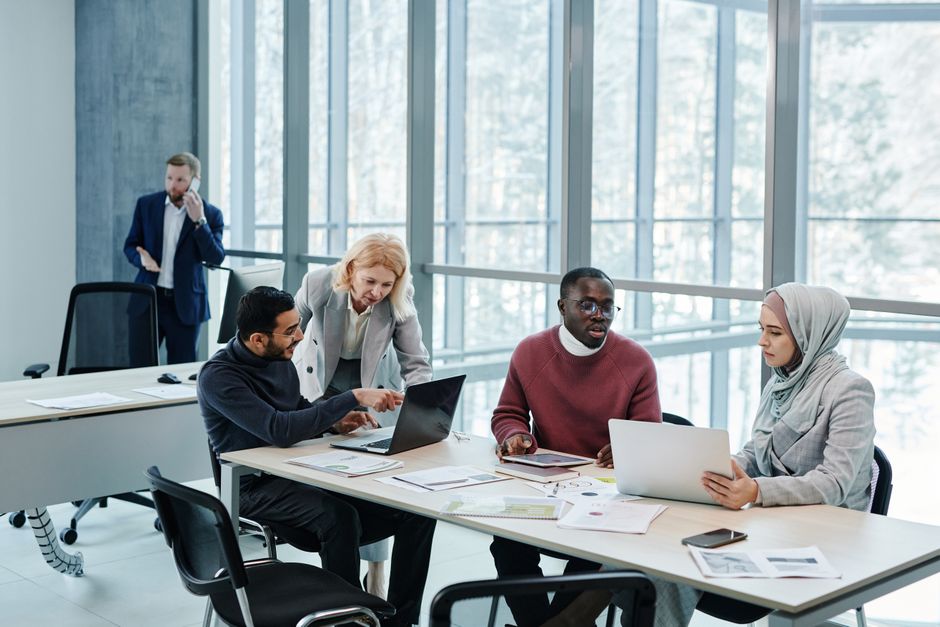 Diverse team of small business professionals collaborating around a table with laptops, illustrating effective meeting dynamics.