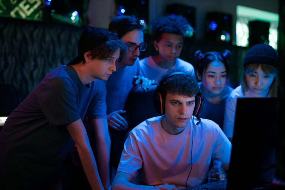A diverse group of children, each on their own device, connected and interacting in an online gaming session, with speech bubbles representing chat.