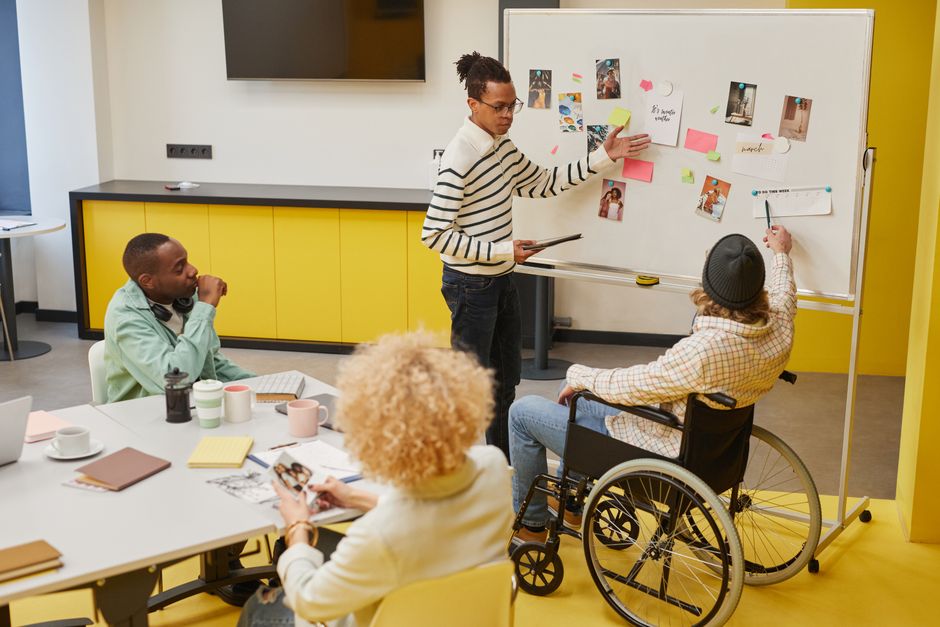 A diverse team of creatives, some looking at screens displaying AI-generated concepts, others sketching ideas, collaborating in a modern studio.
