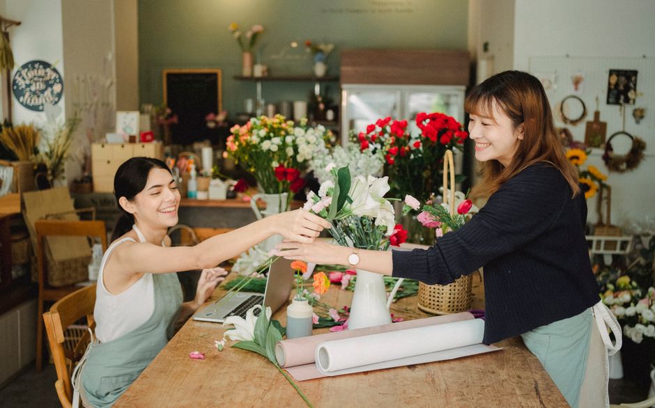 A diverse group of small business owners from different backgrounds collaborating around a table, discussing strategies and looking at a tablet.