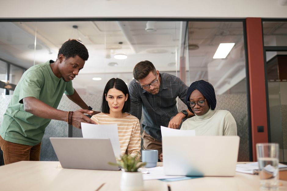 A diverse group of professionals reviewing a digital screen showing AI-generated content, emphasizing human oversight and bias mitigation.