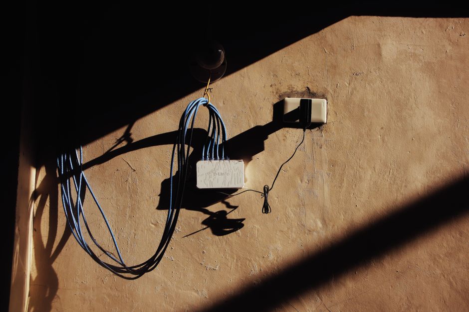 An ethernet cable being discreetly run along a baseboard in an older room, hinting at wired backhaul solutions.