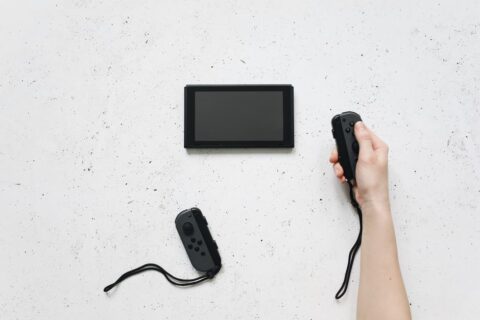 A family, including two parents and two children, laughing and playing a brightly colored video game on a Nintendo Switch console, with French dialogue subtly visible on the screen.