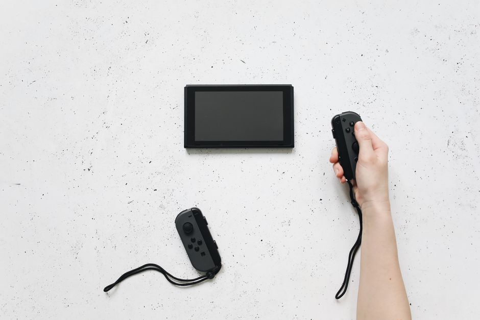 A family, including two parents and two children, laughing and playing a brightly colored video game on a Nintendo Switch console, with French dialogue subtly visible on the screen.