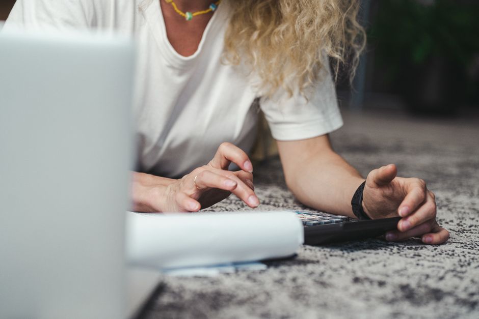 A creative freelancer reviewing financial spreadsheets and invoices on her laptop, surrounded by business notes, symbolizing budget planning.