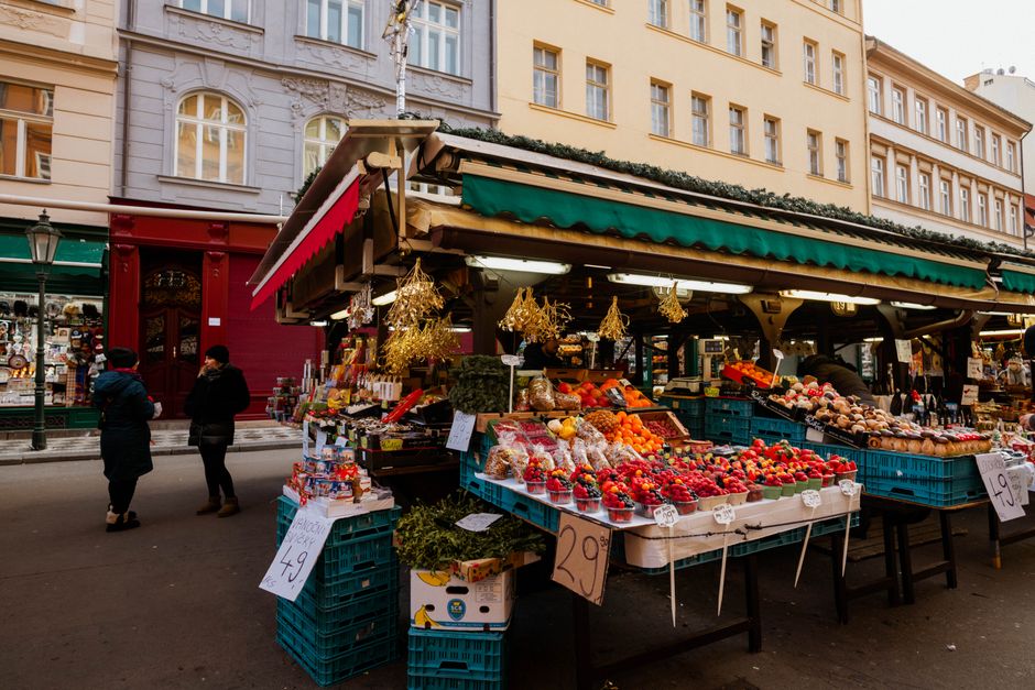 A vibrant display of fresh, colorful fruits and vegetables at a bustling French market stall, including watermelons, tomatoes, and leafy greens, highlighting food as a source of hydration.