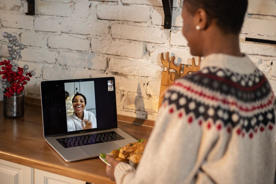 Two young women on separate laptop screens smiling and talking, illustrating long-distance friendship.