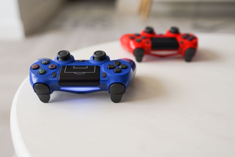 A modern game controller resting on a wooden table, illuminated by the glow of a screen displaying a game selection menu.