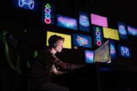 A person sitting in front of a computer screen filled with numerous game icons, looking overwhelmed and indecisive about what to play, illustrating the common gaming backlog problem.