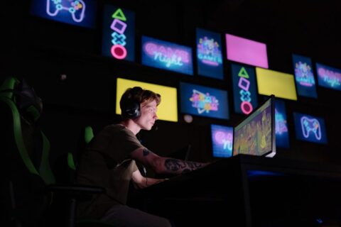 A person sitting in front of a computer screen filled with numerous game icons, looking overwhelmed and indecisive about what to play, illustrating the common gaming backlog problem.