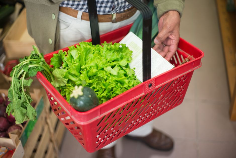 A grocery basket filled with fresh, seasonal produce like vegetables and fruits