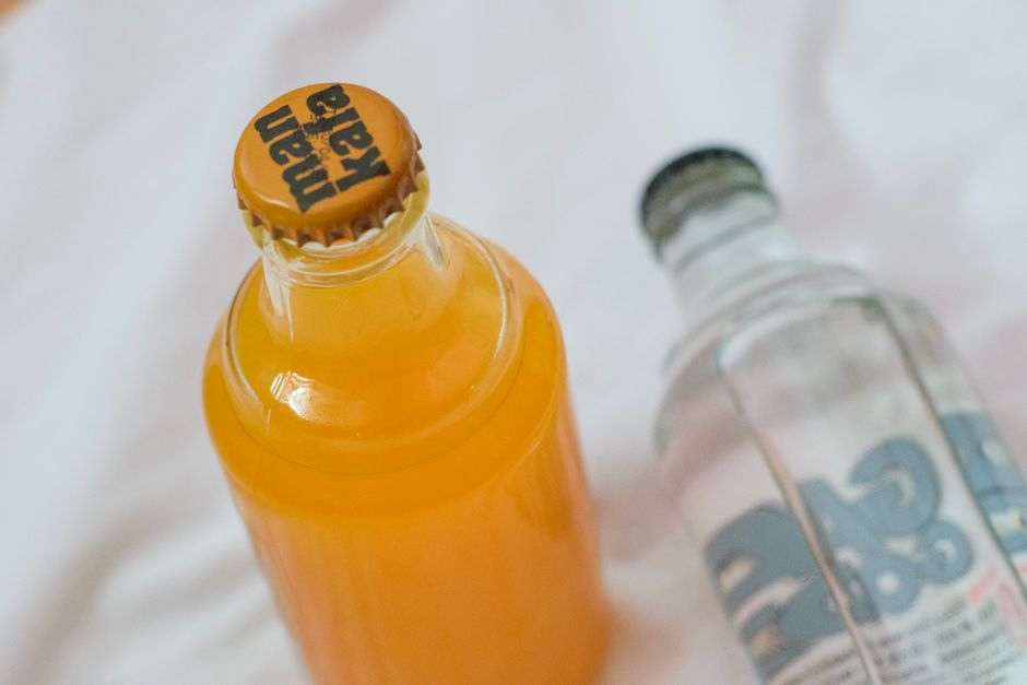 A hand holding a frosty bottle of kombucha against a bright, clean background, suggesting a refreshing and healthy drink choice.