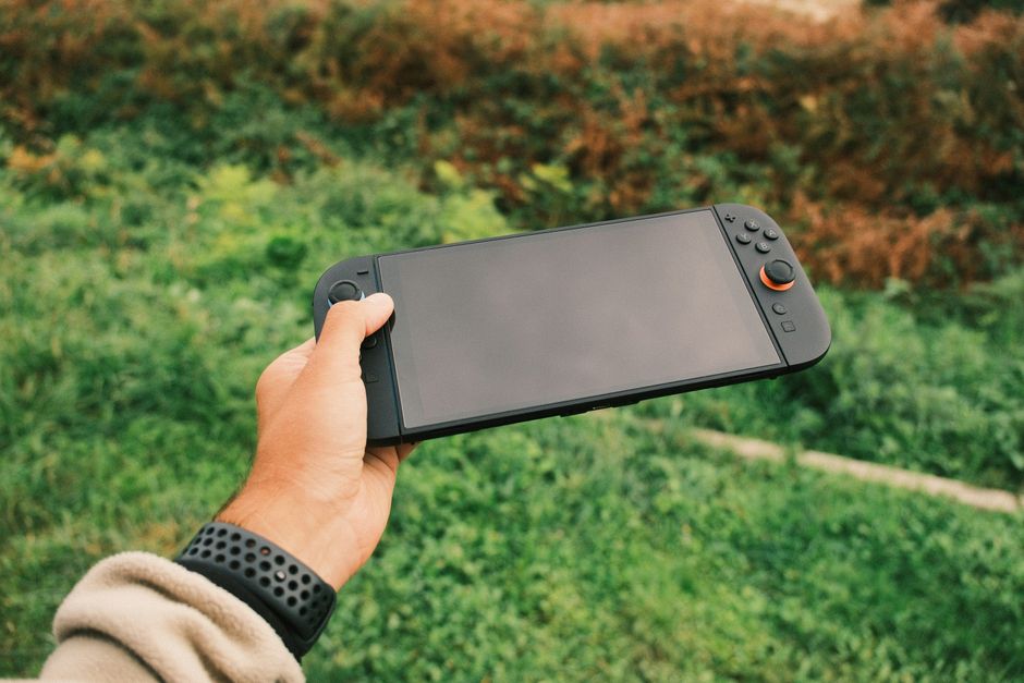 Close-up of hands holding a Nintendo Switch, playing a colorful farming simulation game, illustrating portable and accessible gaming.