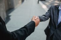 Two professionals shaking hands, signifying the completion of a successful first project and the beginning of a potential long-term partnership.