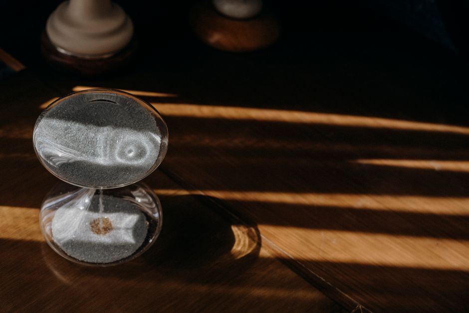 An hourglass placed prominently on a conference table, symbolizing the importance of time management and shorter meetings.