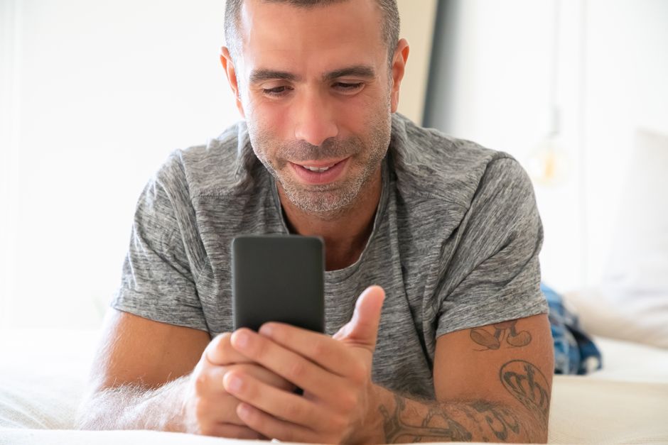 Man holding a smartphone with a translation app open, talking to a market vendor in a foreign country.