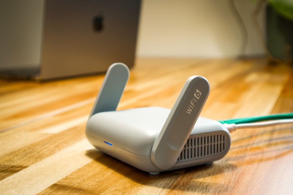 A sleek white mesh Wi-Fi router and two satellite nodes arranged on a modern shelf, showing a typical home setup.