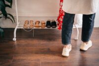 A neatly organized, minimalist shoe rack showcasing a few pairs of high-quality, versatile leather shoes and boots.