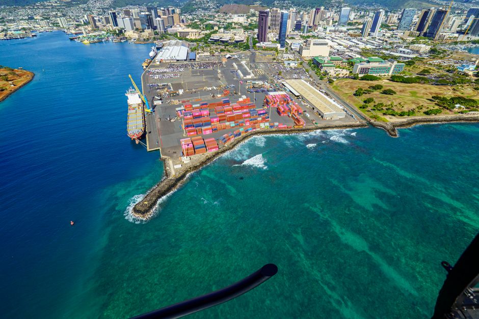 Several distinct islands connected by trade ships and bridges, with different industries and settlements visible on each, illustrating a complex supply chain across a water body.