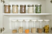 A neatly organized kitchen pantry stocked with olive oils, canned goods, whole grains, and dried herbs, ready for Mediterranean cooking.